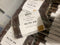 Several packaged chocolate powder bars stacked together. The front package is clear plastic with a white label reading 'Ka kā wā' and '92% cocoa 8% cocoa powder 115g bar'.